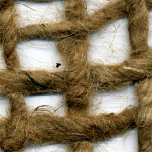 Roll of jute netting mesh laid over soil on a sloped embankment for erosion control