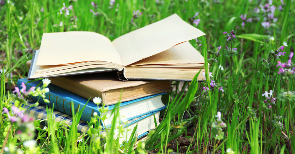 Pile of books in a lawn filled with flowers British Flora