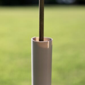 Muted brown biodegradable hedge wrap on a cane in grassland on a hedgerow planting scheme